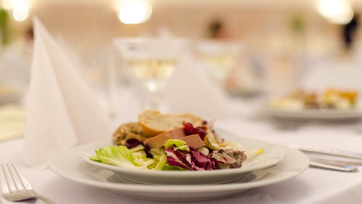 Plate of gourmet salad with bread on a elegantly set restaurant table, perfect for upscale dining experiences.